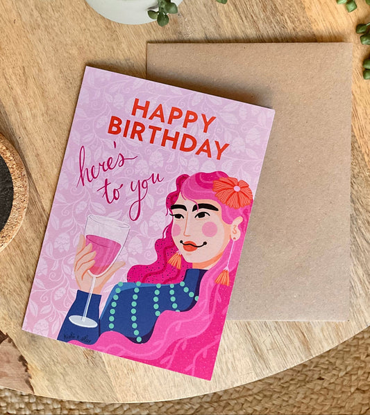 Birthday card with illustration of a person holding a drink on a wooden surface with a plant.