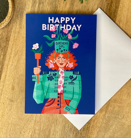Birthday card with illustration of a person holding flowers on a wooden surface with a plant.